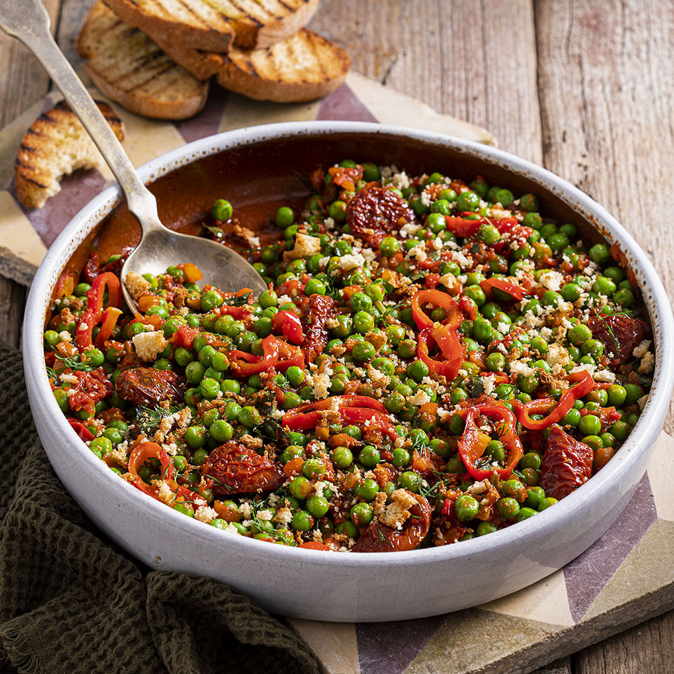 Peas in a clay pot with sun-dried tomatoes and spicy peppers